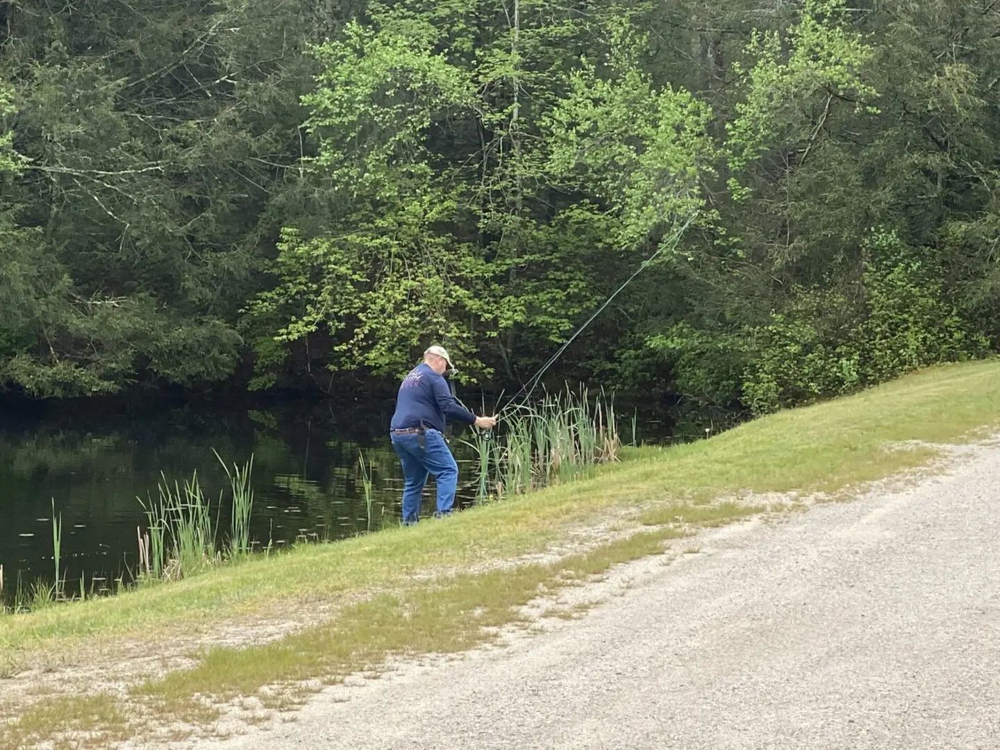 A Man in Blue Shirt and Jeans Fishing With Fishing Rope