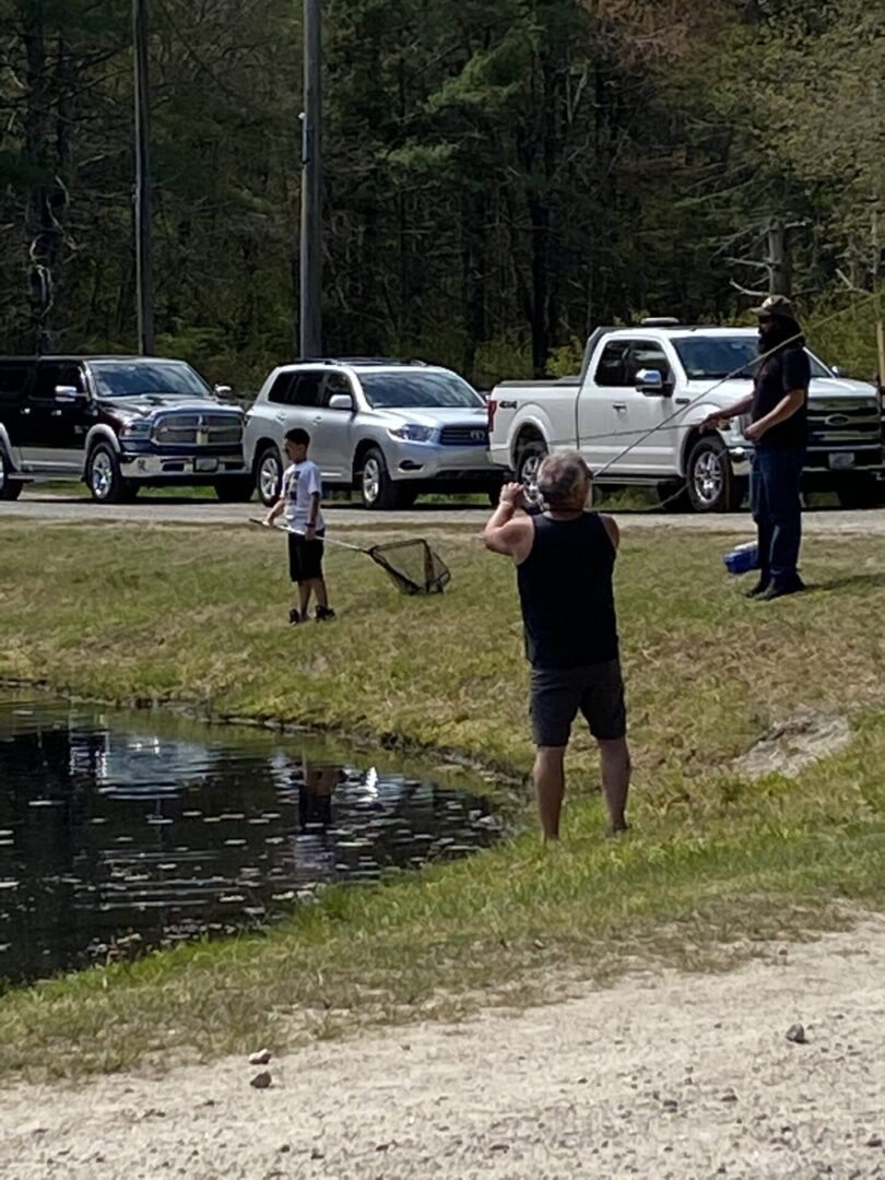 A Group of People Standing by the Banks of a Pond For Fishing
