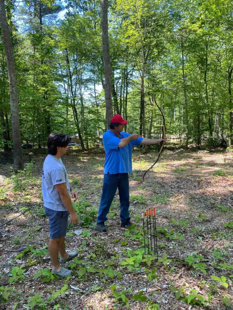 A person in blue T-shirt practicing archery in the forest